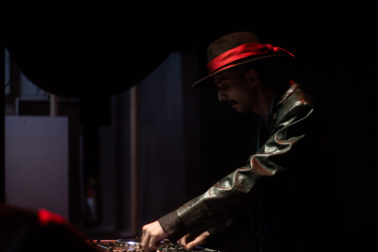 DJ de chapéu inclinado sobre a mesa de som — Sad Baile Joker, Halloween em São Paulo, 17/10/2026