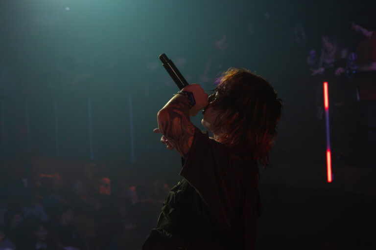 Rapper canta de olhos fechados sob luz verde — Sad Baile Joker, Halloween em São Paulo, 17/10/2026