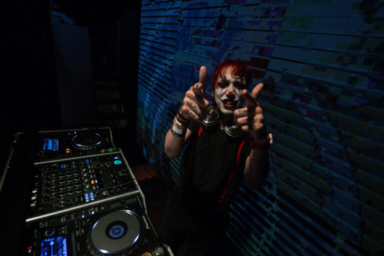 DJ com maquiagem de palhaço aponta para a câmera — Sad Baile Joker, Halloween em São Paulo, 17/10/2026