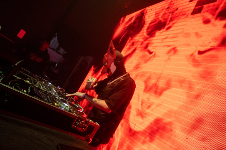 DJ sob a luz laranja do telão — Sad Baile Joker, Halloween em São Paulo, 17/10/2026