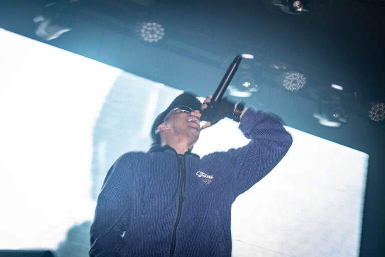 Rapper de boné canta diante do telão branco — Sad Baile Joker, Halloween em São Paulo, 17/10/2026