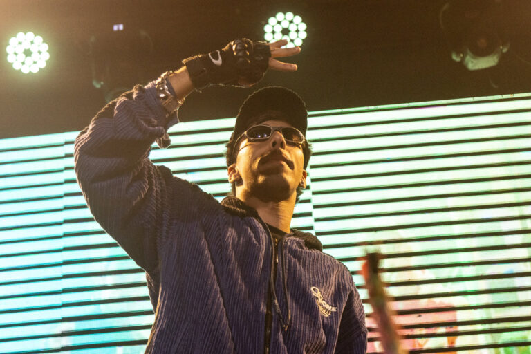 Rapper ergue o braço diante do telão listrado — Sad Baile Joker, Halloween em São Paulo, 17/10/2026