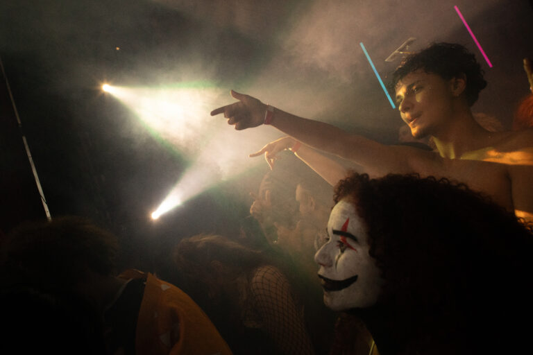 Garota de maquiagem branca aponta sob os refletores — Sad Baile Joker, Halloween em São Paulo, 17/10/2026