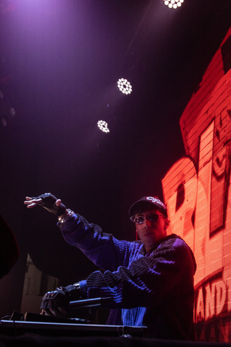 DJ aponta para a plateia sob luz roxa — Sad Baile Joker, Halloween em São Paulo, 17/10/2026