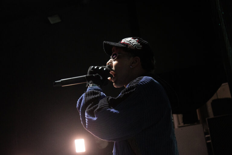 Rapper canta com o microfone sob luz baixa — Sad Baile Joker, Halloween em São Paulo, 17/10/2026