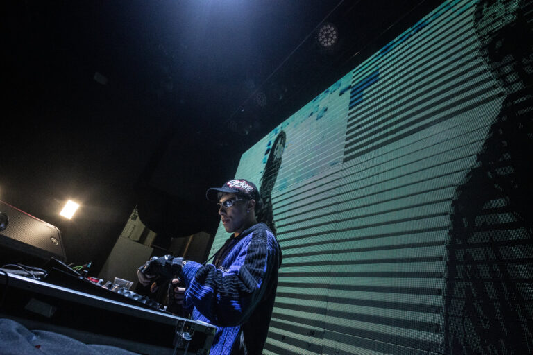 DJ toca diante do telão listrado — Sad Baile Joker, Halloween em São Paulo, 17/10/2026