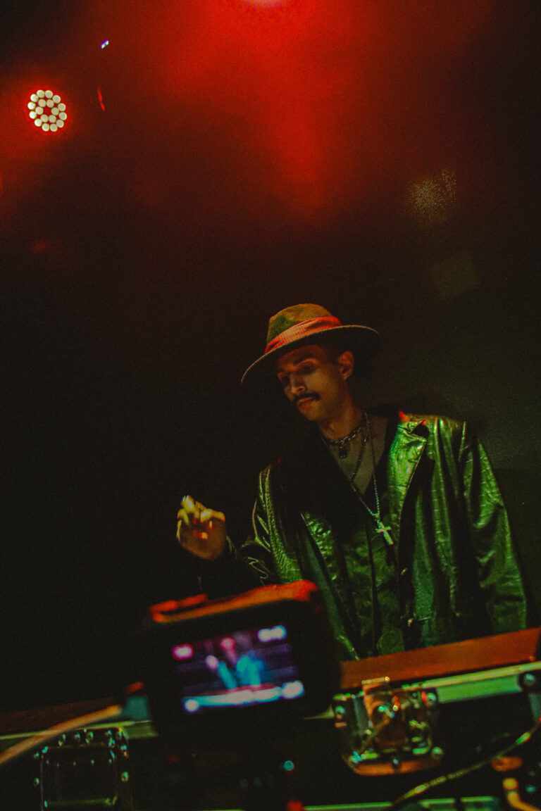 DJ de chapéu sorri na cabine com luz vermelha ao fundo — Sad Baile Joker, Halloween em São Paulo, 17/10/2026