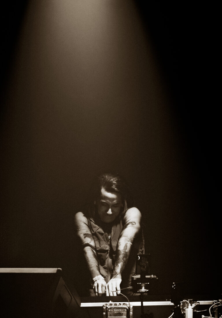 DJ debruçado sobre a mesa sob um facho de luz — Sad Baile Joker, Halloween em São Paulo, 17/10/2026