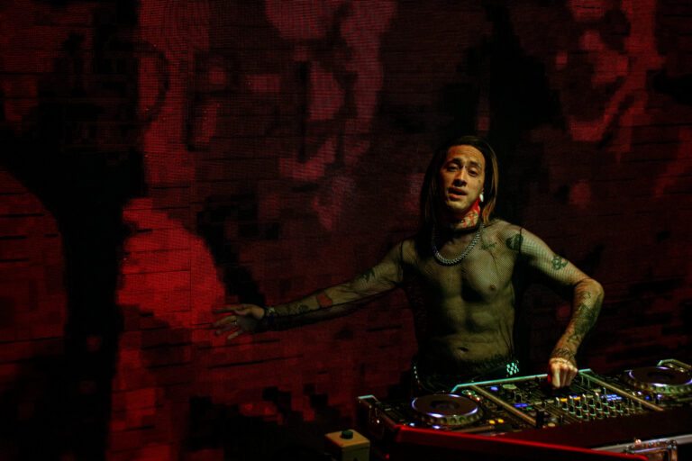 DJ tatuado gesticula sobre a mesa de som — Sad Baile Joker, Halloween em São Paulo, 17/10/2026