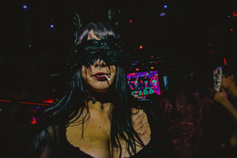 Convidada de máscara de renda na pista com telão ao fundo — Sad Baile Joker, Halloween em São Paulo, 17/10/2026