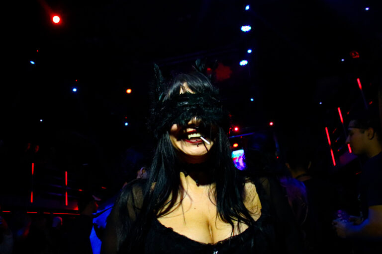 Convidada de orelhas de gato e máscara sob luzes azuis — Sad Baile Joker, Halloween em São Paulo, 17/10/2026