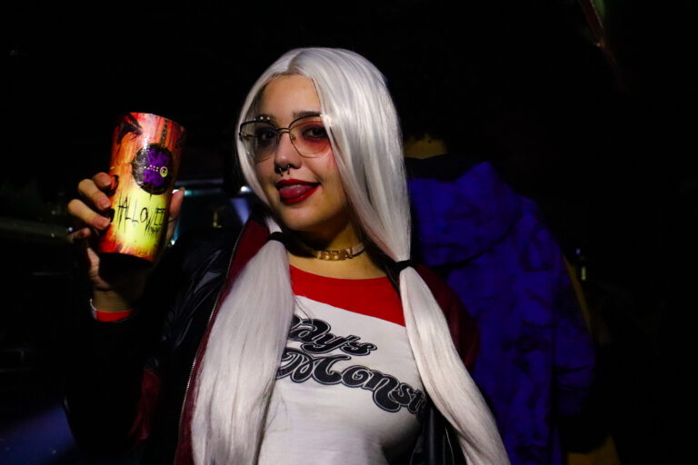 Fantasia de Arlequina de óculos posa com a bebida — Sad Baile Joker, Halloween em São Paulo, 17/10/2026