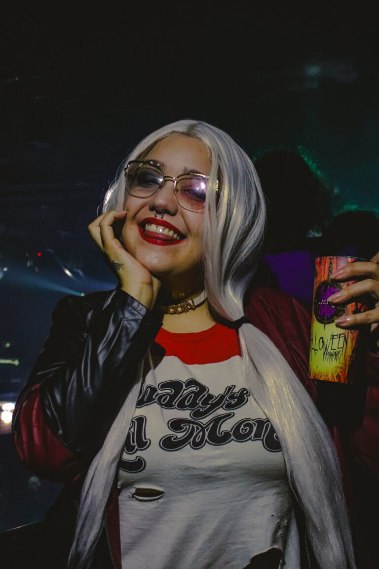 Arlequina de óculos sorri com a mão no rosto — Sad Baile Joker, Halloween em São Paulo, 17/10/2026