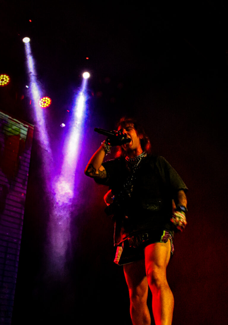 Artista canta sob dois feixes de luz roxa — Sad Baile Joker, Halloween em São Paulo, 17/10/2026