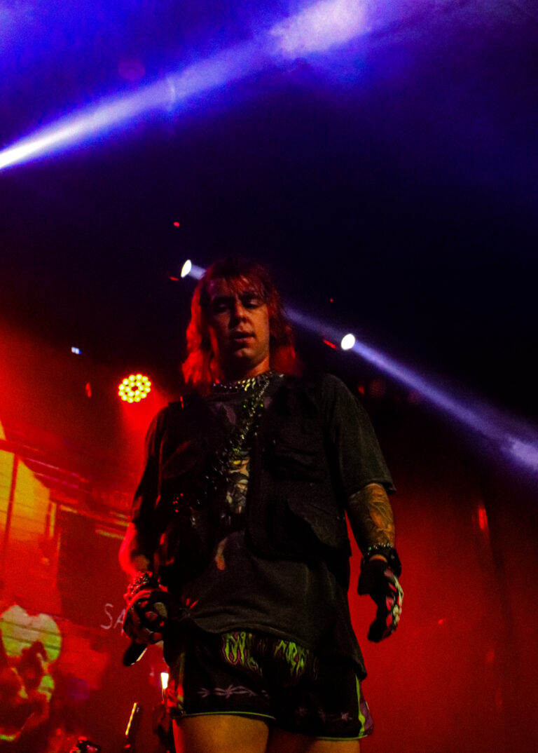 Rapper de cabelo comprido no palco sob luz vermelha e roxa — Sad Baile Joker, Halloween em São Paulo, 17/10/2026