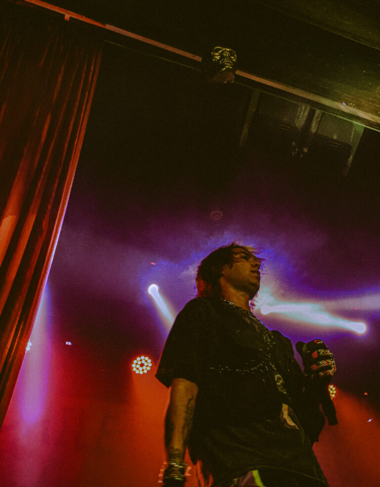 Rapper de perfil sob luz quente e cortina vermelha — Sad Baile Joker, Halloween em São Paulo, 17/10/2026