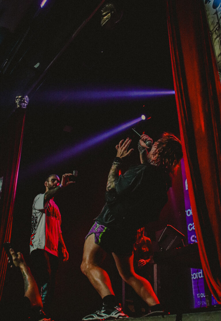 Dois artistas pulam no palco entre as cortinas vermelhas — Sad Baile Joker, Halloween em São Paulo, 17/10/2026