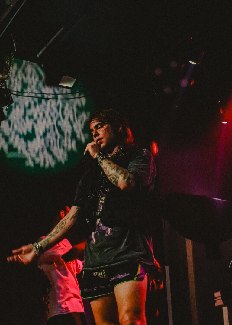 Rapper tatuado canta na beira do palco com telão verde — Sad Baile Joker, Halloween em São Paulo, 17/10/2026