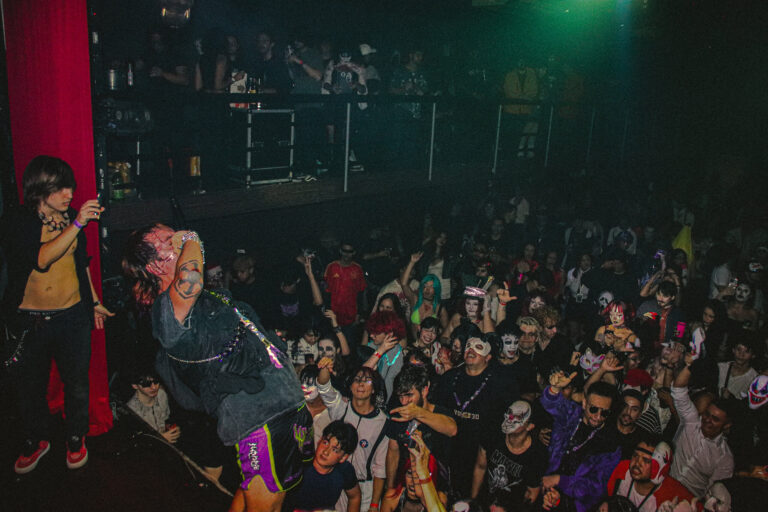 Rapper no palco diante da pista cheia sob luz verde — Sad Baile Joker, Halloween em São Paulo, 17/10/2026
