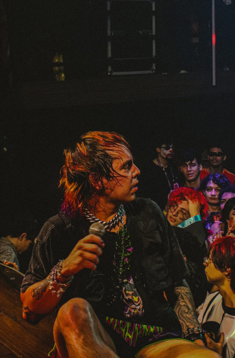 Rapper sentado na grade com o público atrás — Sad Baile Joker, Halloween em São Paulo, 17/10/2026