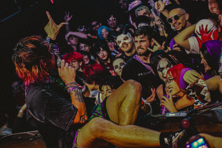 Público de máscaras faz chifrinho ao lado do rapper — Sad Baile Joker, Halloween em São Paulo, 17/10/2026