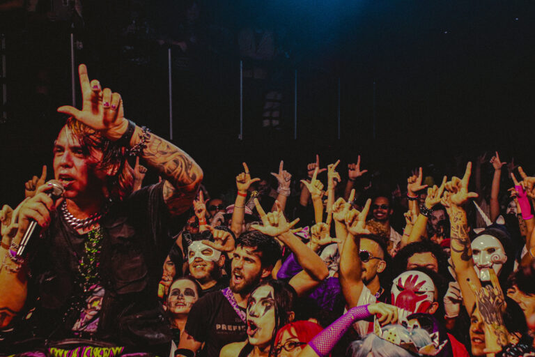 Rapper de dedo erguido diante do público fantasiado — Sad Baile Joker, Halloween em São Paulo, 17/10/2026