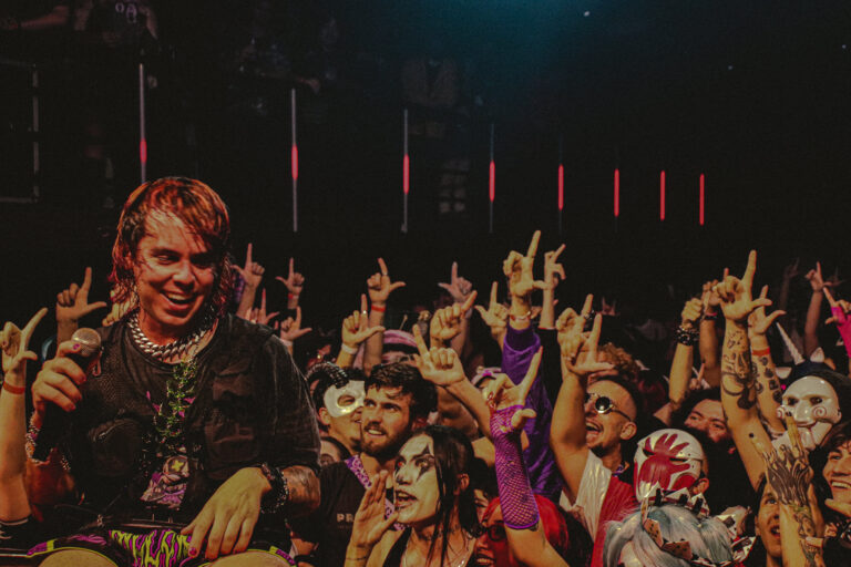 Rapper sorridente com a multidão fantasiada atrás — Sad Baile Joker, Halloween em São Paulo, 17/10/2026