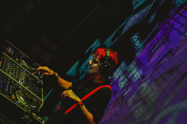 DJ de cabelo vermelho na cabine diante do telão roxo — Sad Baile Joker, Halloween em São Paulo, 17/10/2026