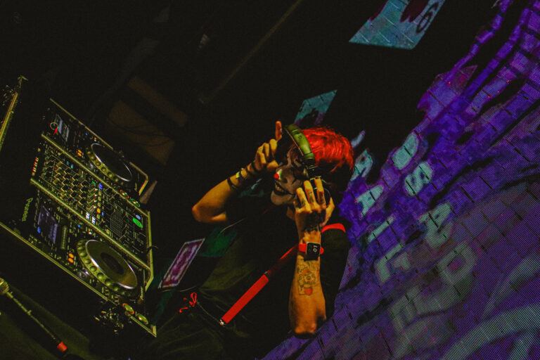 DJ de cabelo vermelho e suspensórios na mesa de som — Sad Baile Joker, Halloween em São Paulo, 17/10/2026
