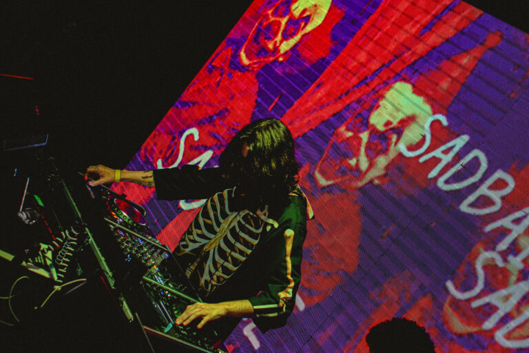 DJ com fantasia de esqueleto mixando sob o telão colorido — Sad Baile Joker, Halloween em São Paulo, 17/10/2026
