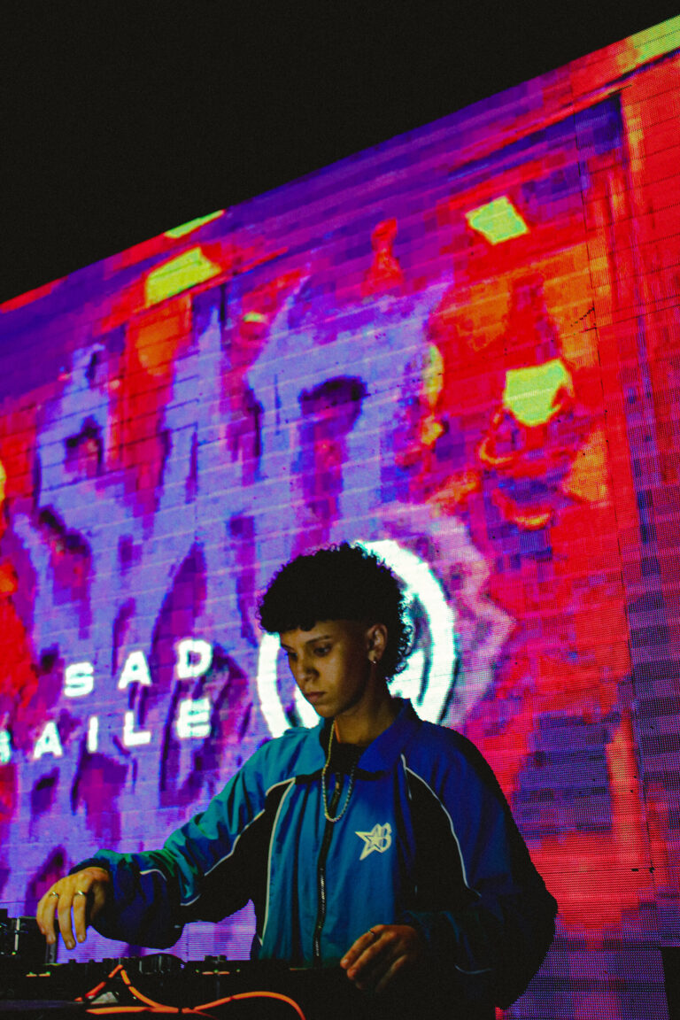DJ de jaqueta azul com o logo Sad Baile em néon atrás — Sad Baile Joker, Halloween em São Paulo, 17/10/2026