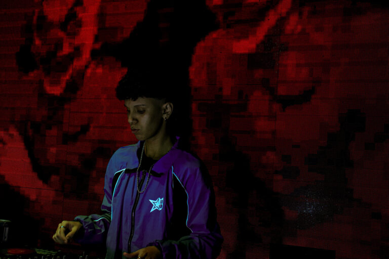 DJ de jaqueta roxa com telão vermelho escuro — Sad Baile Joker, Halloween em São Paulo, 17/10/2026
