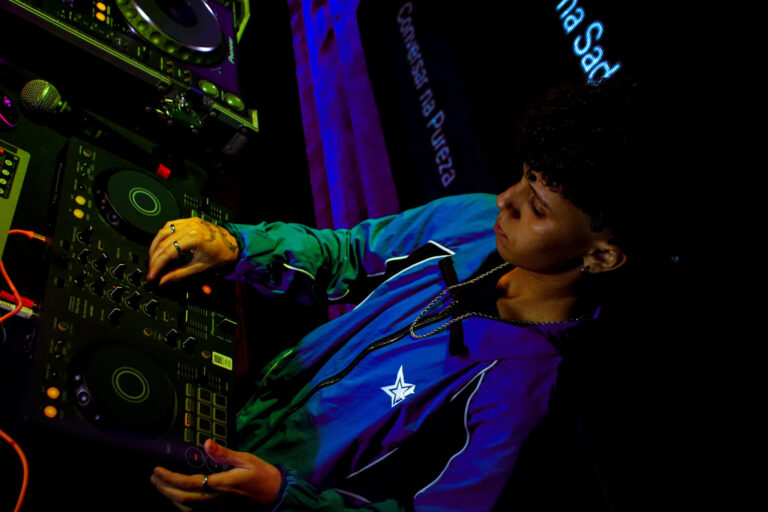 DJ de jaqueta inclinado sobre os controles — Sad Baile Joker, Halloween em São Paulo, 17/10/2026