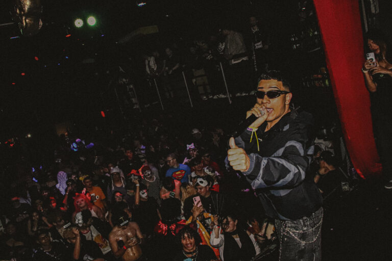 Rapper de óculos canta ao lado da cortina vermelha — Sad Baile Joker, Halloween em São Paulo, 17/10/2026