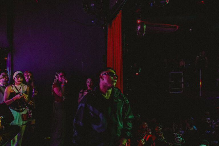 Artistas no palco sob luz roxa e cortina vermelha — Sad Baile Joker, Halloween em São Paulo, 17/10/2026