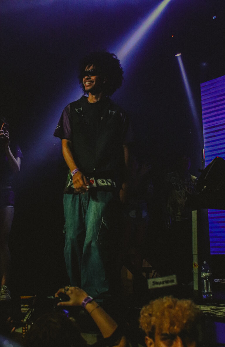 Rapper de calça larga parado no palco sob feixe de luz — Sad Baile Joker, Halloween em São Paulo, 17/10/2026