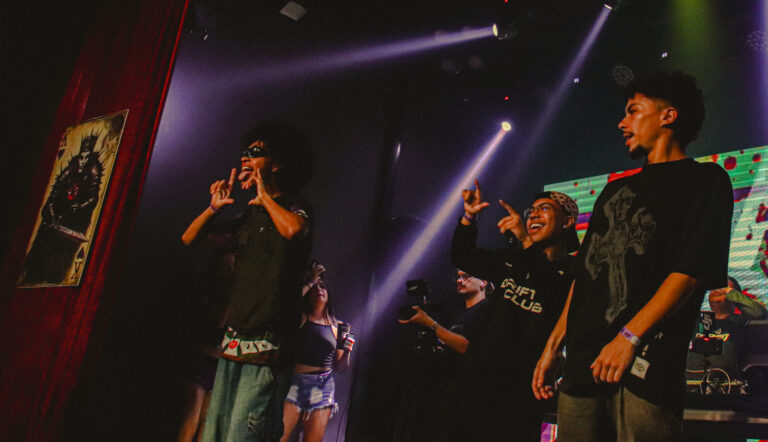 Artistas cantam lado a lado sob feixes de luz roxa — Sad Baile Joker, Halloween em São Paulo, 17/10/2026