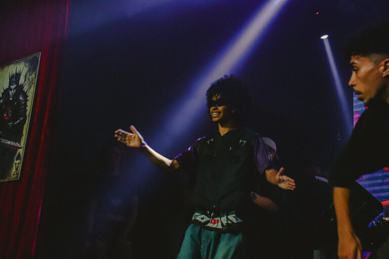 Artista gesticula no palco junto à cortina vermelha — Sad Baile Joker, Halloween em São Paulo, 17/10/2026