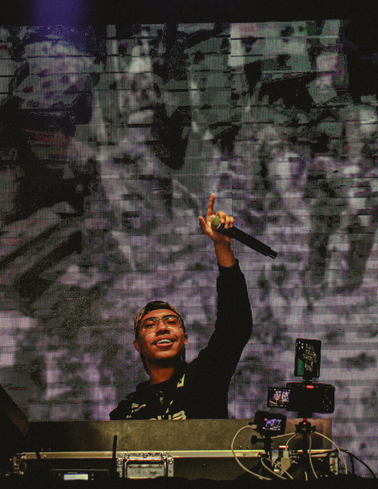 DJ sorri com o microfone erguido diante do telão — Sad Baile Joker, Halloween em São Paulo, 17/10/2026
