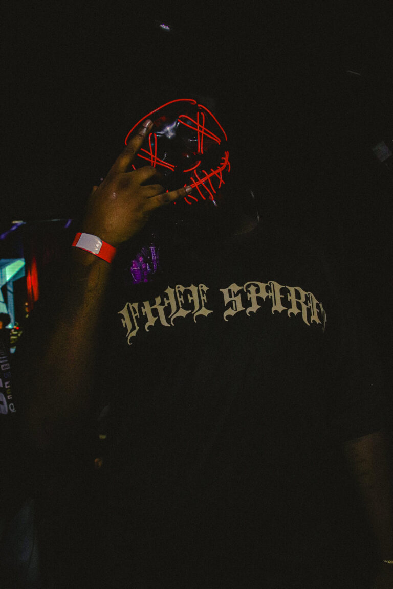 Convidado com máscara de néon vermelha e camiseta bordada — Sad Baile Joker, Halloween em São Paulo, 17/10/2026
