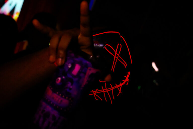 Máscara de néon vermelho e mão fazendo sinal — Sad Baile Joker, Halloween em São Paulo, 17/10/2026