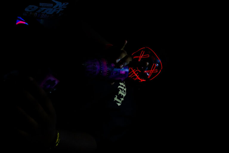Brilho fraco da máscara de néon na penumbra — Sad Baile Joker, Halloween em São Paulo, 17/10/2026