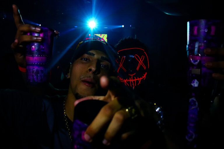Grupo com máscara de néon e luz azul ao fundo — Sad Baile Joker, Halloween em São Paulo, 17/10/2026