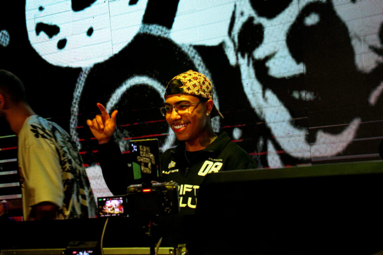 DJ de bandana sorri diante do telão de caveiras — Sad Baile Joker, Halloween em São Paulo, 17/10/2026