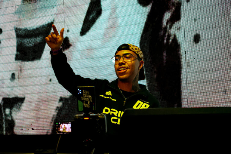 DJ de bandana com o braço erguido e telão em preto e branco — Sad Baile Joker, Halloween em São Paulo, 17/10/2026