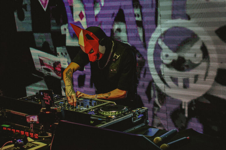 DJ de máscara de diabo vermelha mixando diante do telão — Sad Baile Joker, Halloween em São Paulo, 17/10/2026