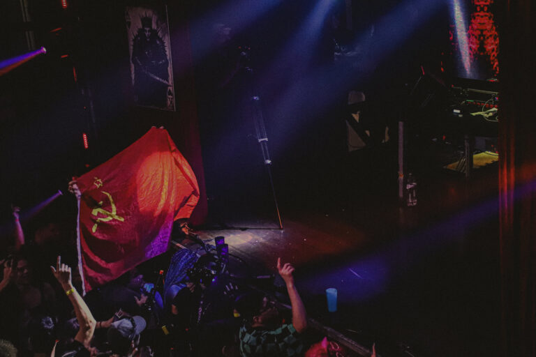 Bandeira vermelha agitada na pista sob luz azul — Sad Baile Joker, Halloween em São Paulo, 17/10/2026