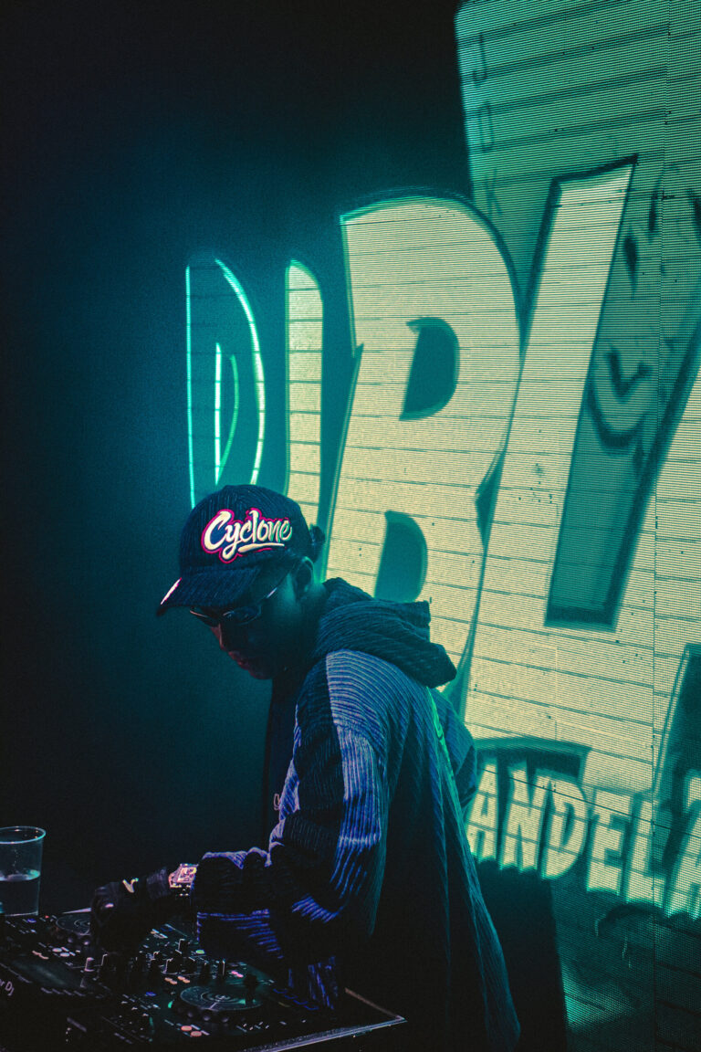 DJ de boné diante do telão verde com o nome do DJ — Sad Baile Joker, Halloween em São Paulo, 17/10/2026