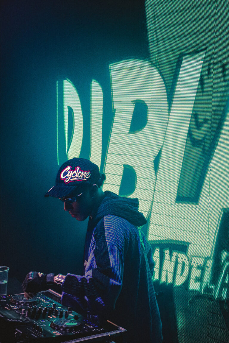 DJ de boné nos controles com telão verde — Sad Baile Joker, Halloween em São Paulo, 17/10/2026