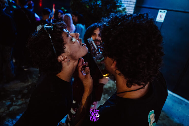 Dois amigos brindam na área externa à noite — Sad Baile Joker, Halloween em São Paulo, 17/10/2026